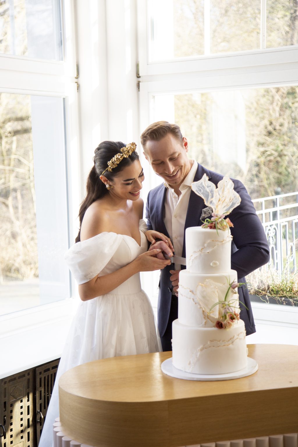 Hochzeitsfoto von Sarah Seiler Fotografie Ein Hochzeitspaar schneidet gemeinsam seine Hochzeitstorte an und Sarah Seiler Fotografie hält diesen Moment fest.