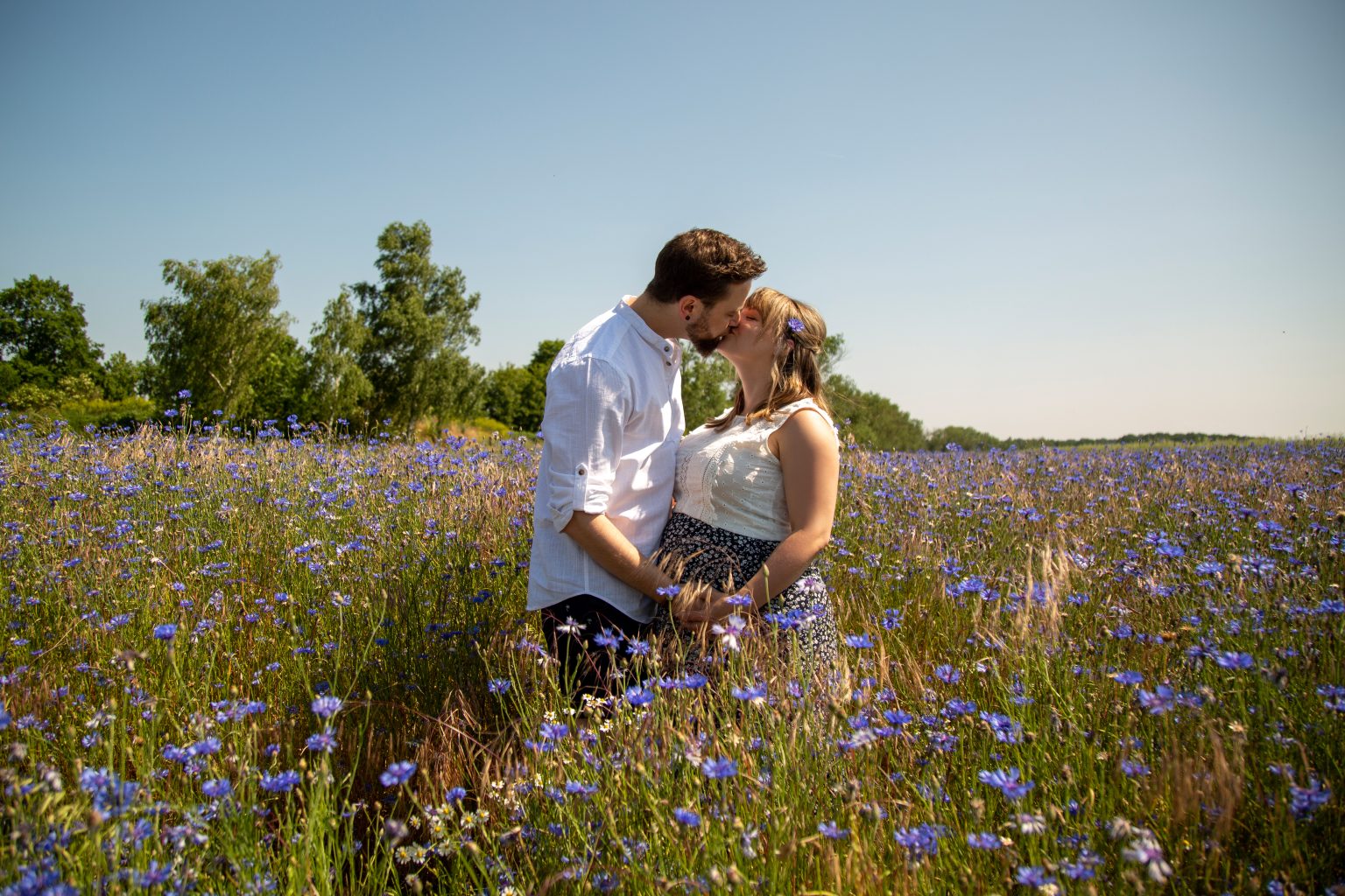 Paarshooting von Sarah Seiler Fotografie Eine schwangere Frau sitzt draußen und Sarah Seiler Fotografie fotografiert sie.