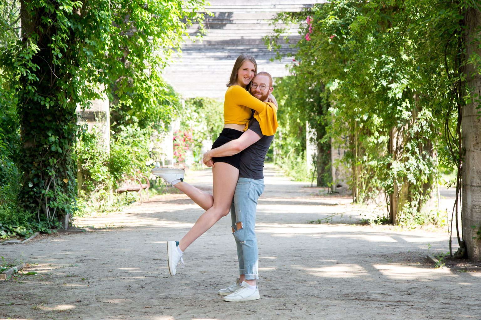 Paarshooting von Sarah Seiler Fotografie Ein Paar lacht draußen und er hebt seine Partnerin hoch, während Sarah Seiler Fotografie diesen Moment festhält.