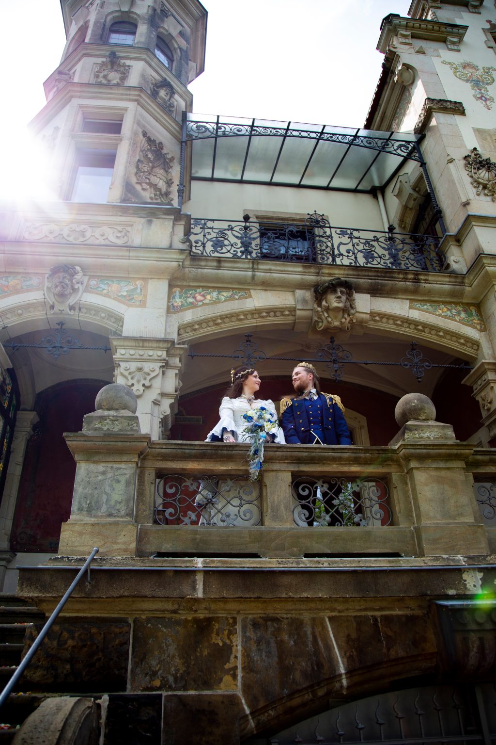 Hochzeitsfoto von Sarah Seiler Fotografie Ein Hochzeitspaar steht auf einem historischen Balkon und Sarah Seiler Fotografie fotografiert sie.