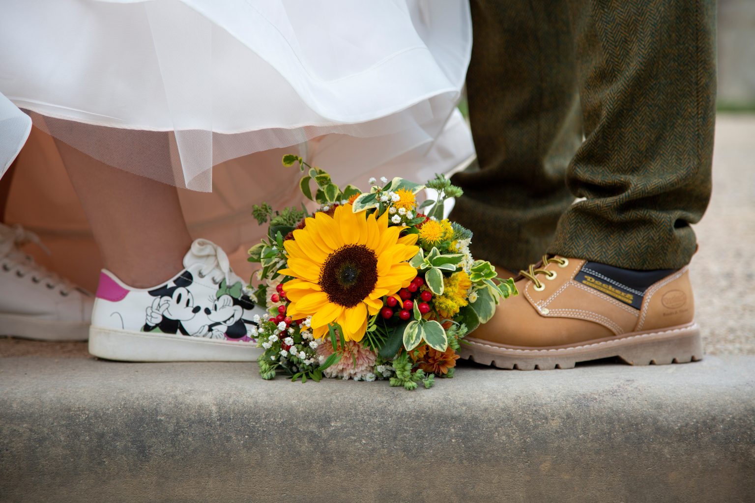 Hochzeitsfoto von Sarah Seiler Fotografie Eine Braut hält ihren Strauß und Sarah Seiler Fotografie fotografiert ihre Schuhe und Blumen.