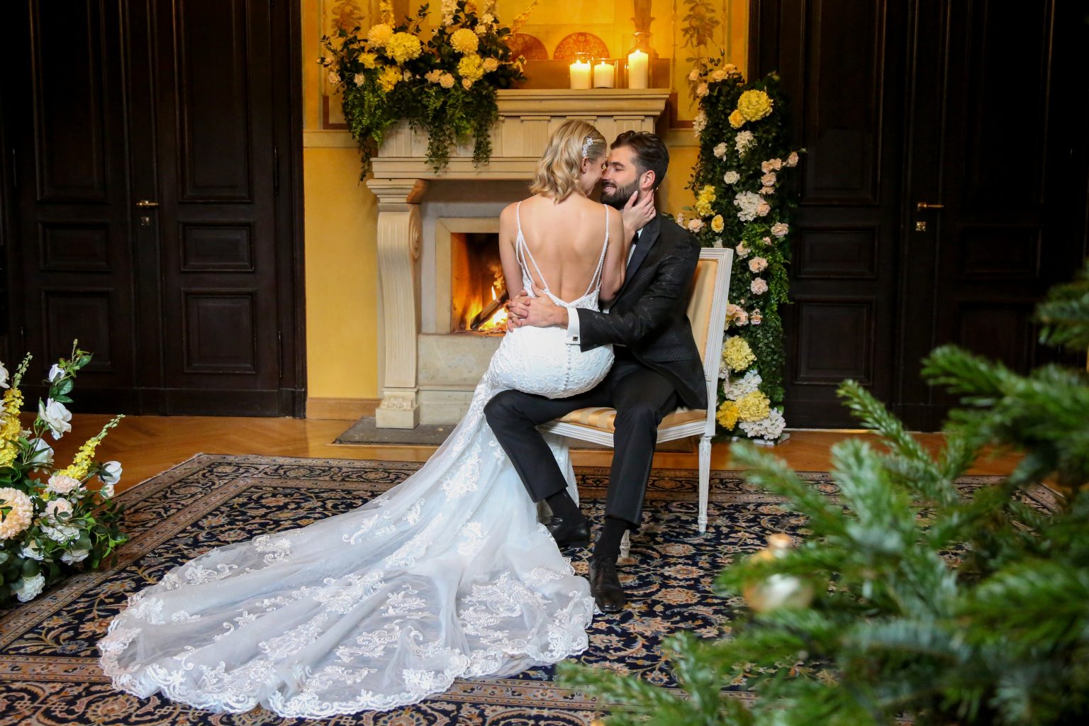 Hochzeitsfoto von Sarah Seiler Fotografie Ein Hochzeitspaar sitzt vor einem Kamin und Sarah Seiler Fotografie hält diesen Moment fest.