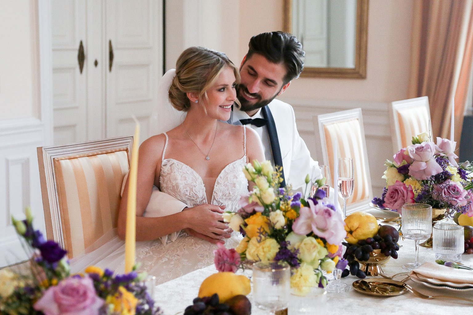 Hochzeitsfoto von Sarah Seiler Fotografie Ein Hochzeitspaar sitzt an einer festlich dekorierten Tafel und Sarah Seiler Fotografie hält den Moment fest.