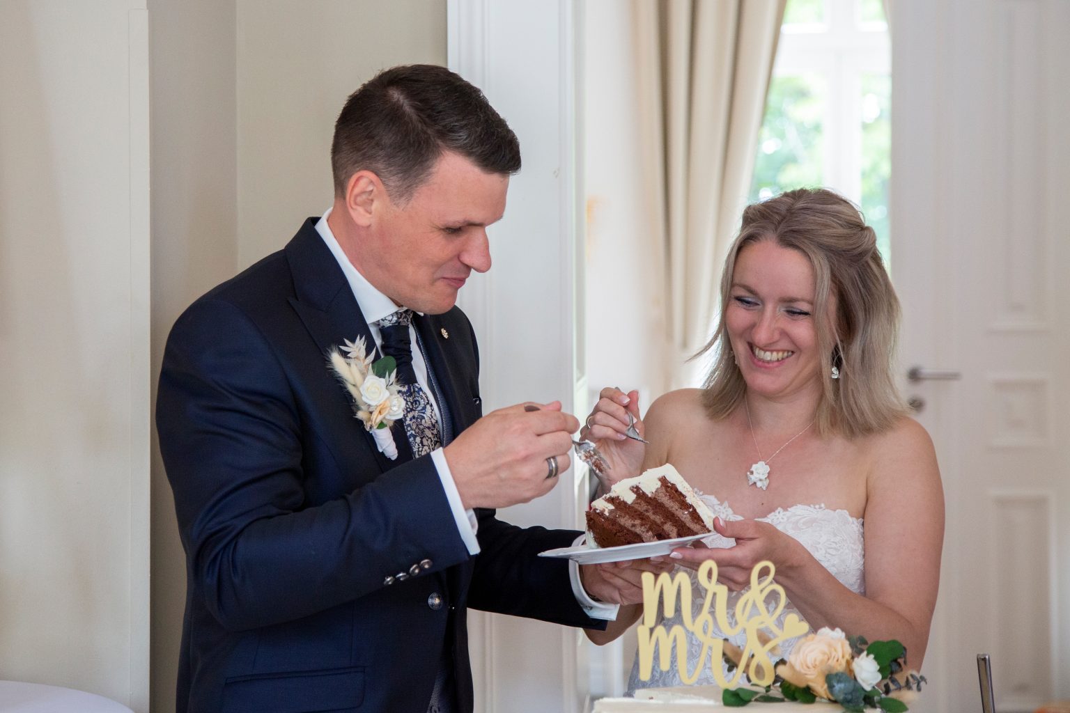 Hochzeitsfoto von Sarah Seiler Fotografie Ein Paar probiert Hochzeitstorte und Sarah Seiler Fotografie fotografiert sie.