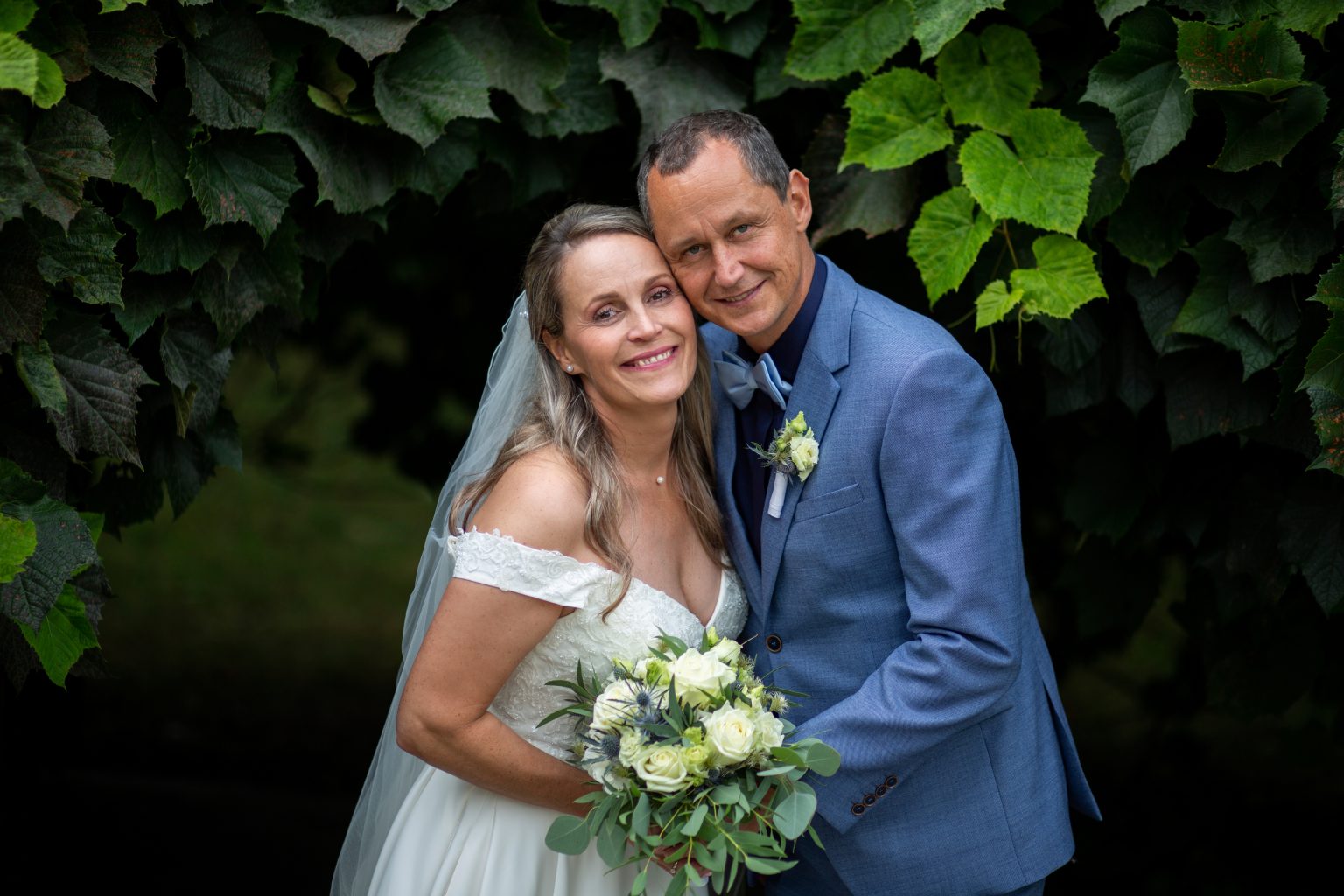 Hochzeitsfoto von Sarah Seiler Fotografie Ein Hochzeitspaar steht eng umarmt im Grünen und Sarah Seiler Fotografie fotografiert sie.