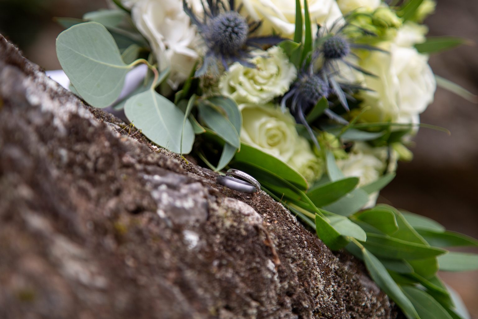 Hochzeit_Jana_und_Konrad-320 Ein floraler Hochzeitsstrauß liegt auf einem Felsen und Sarah Seiler Fotografie fotografiert ihn.