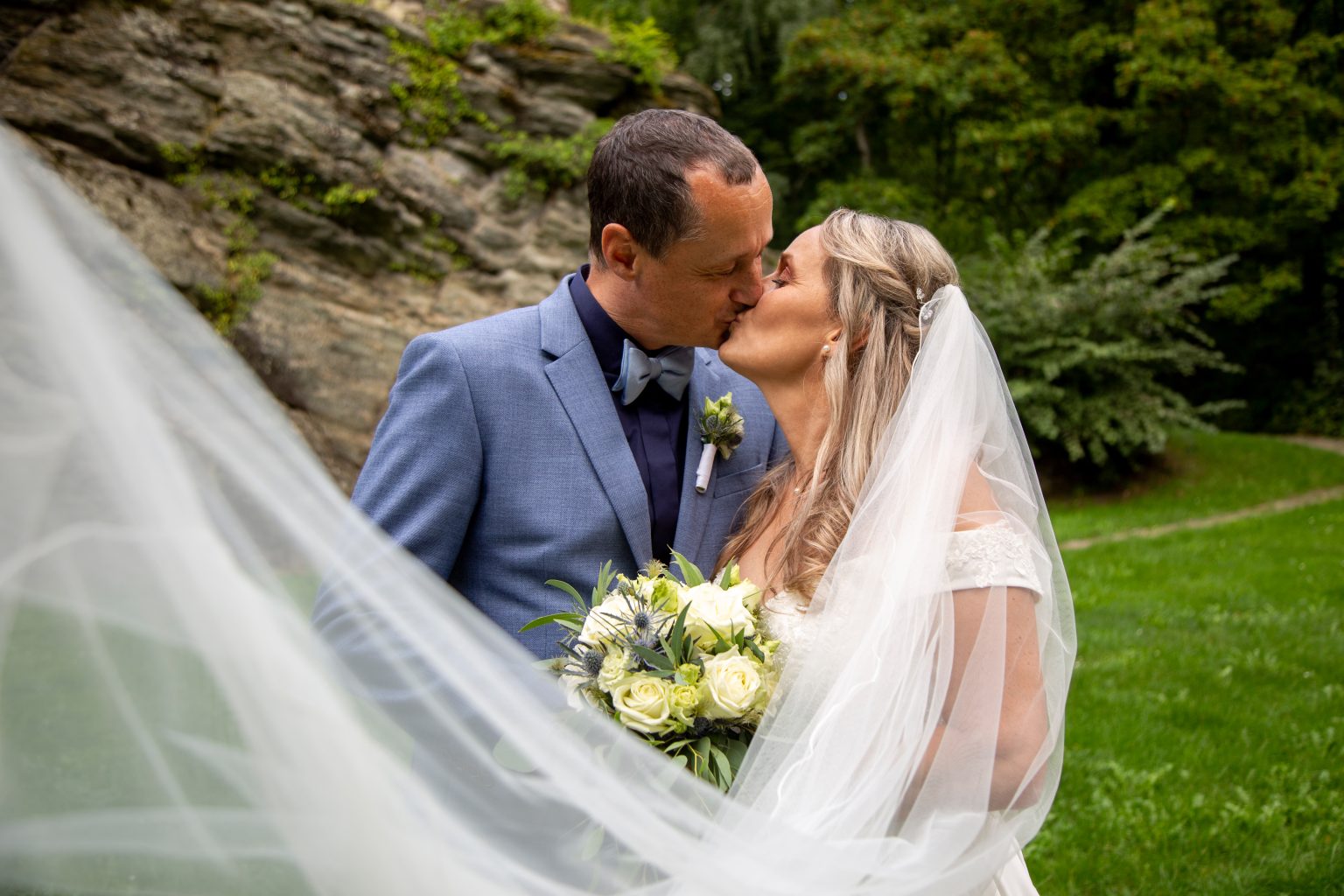 Hochzeitsfoto von Sarah Seiler Fotografie Ein Hochzeitspaar küsst sich draußen und Sarah Seiler Fotografie hält diesen Moment fest.
