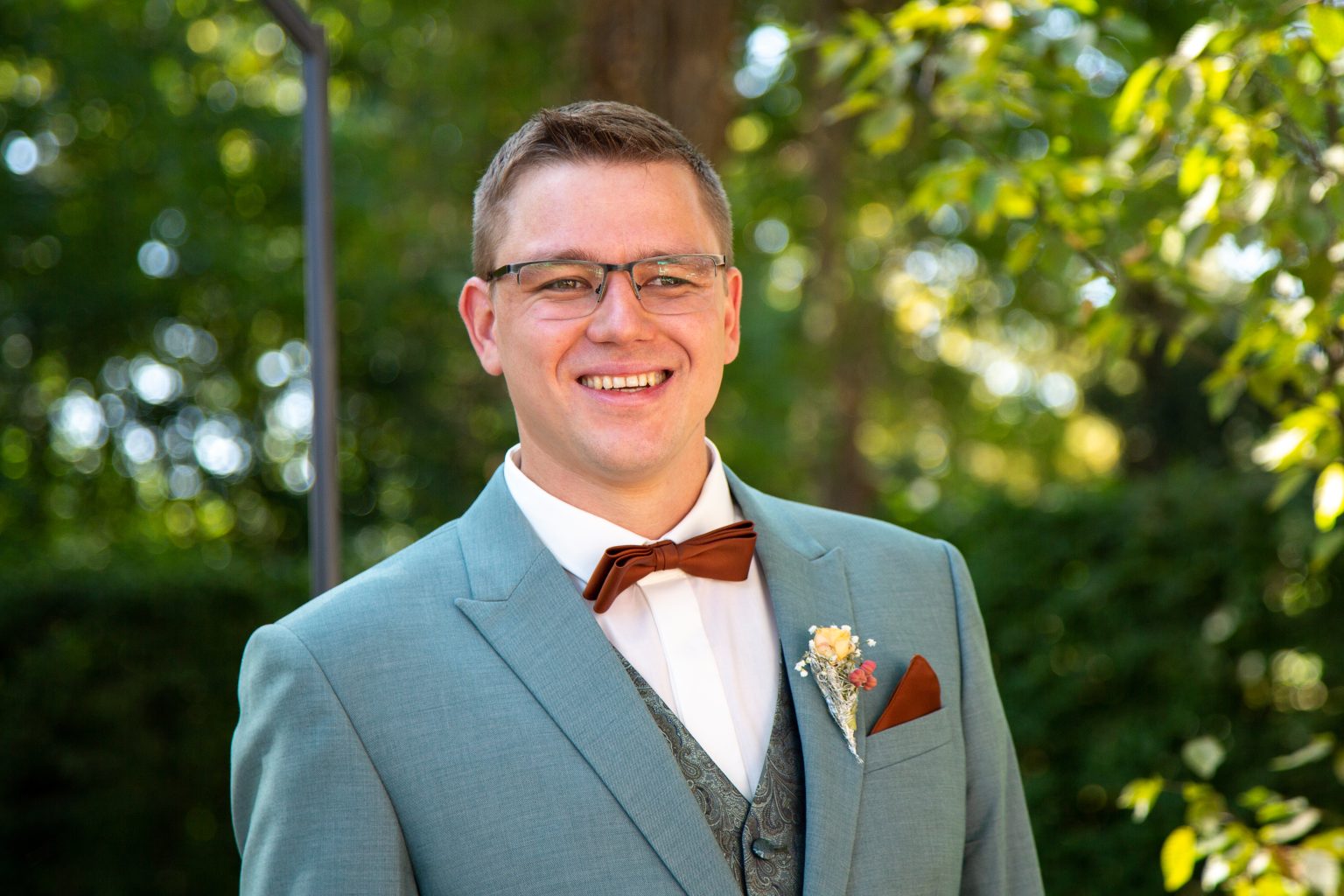 Bräutigamfoto – Sarah Seiler Fotografie Ein Bräutigam lächelt in die Kamera und Sarah Seiler Fotografie fotografiert ihn.