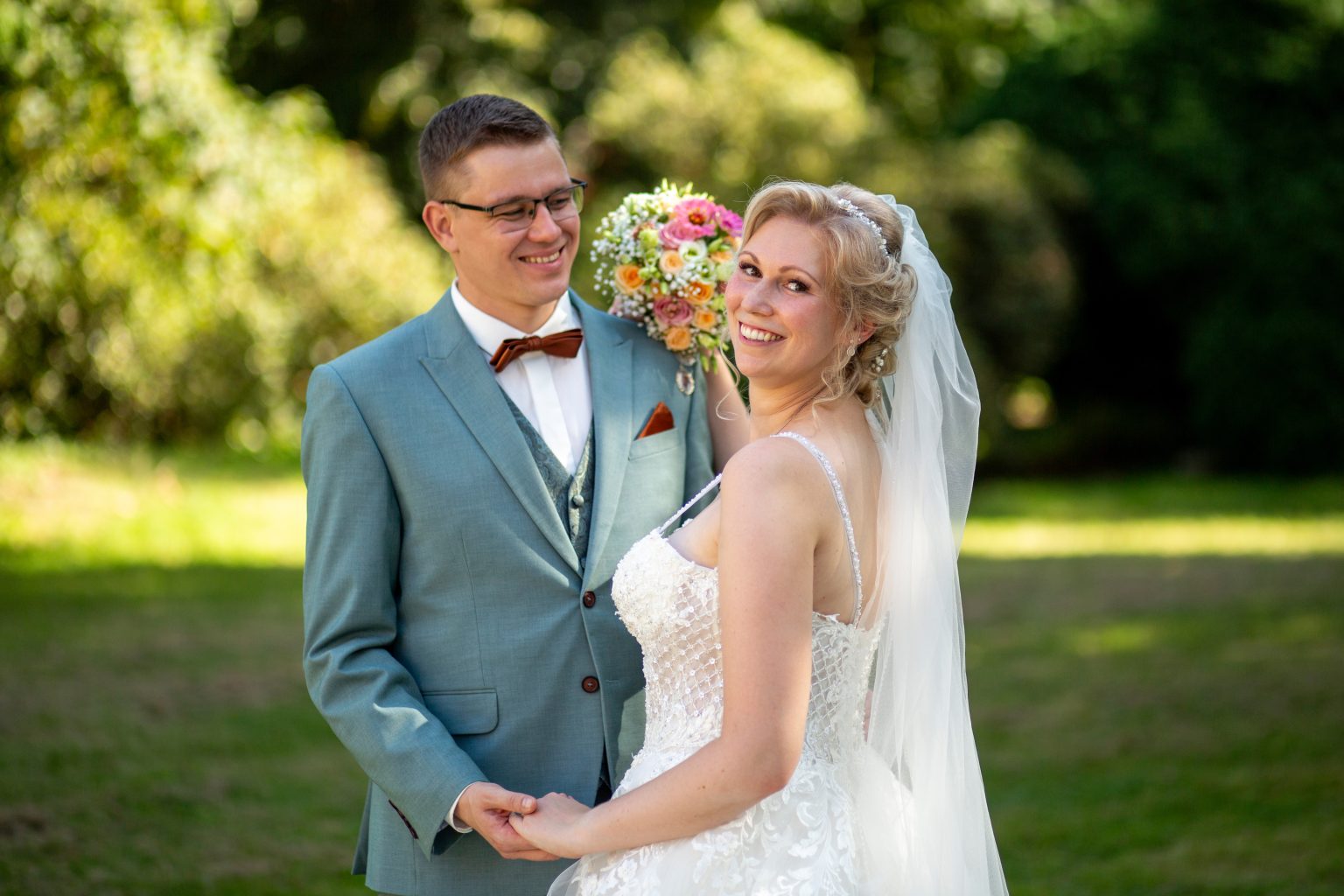 Hochzeitsfoto von Sarah Seiler Fotografie Ein Hochzeitspaar steht draußen und lacht, während Sarah Seiler Fotografie sie fotografiert.