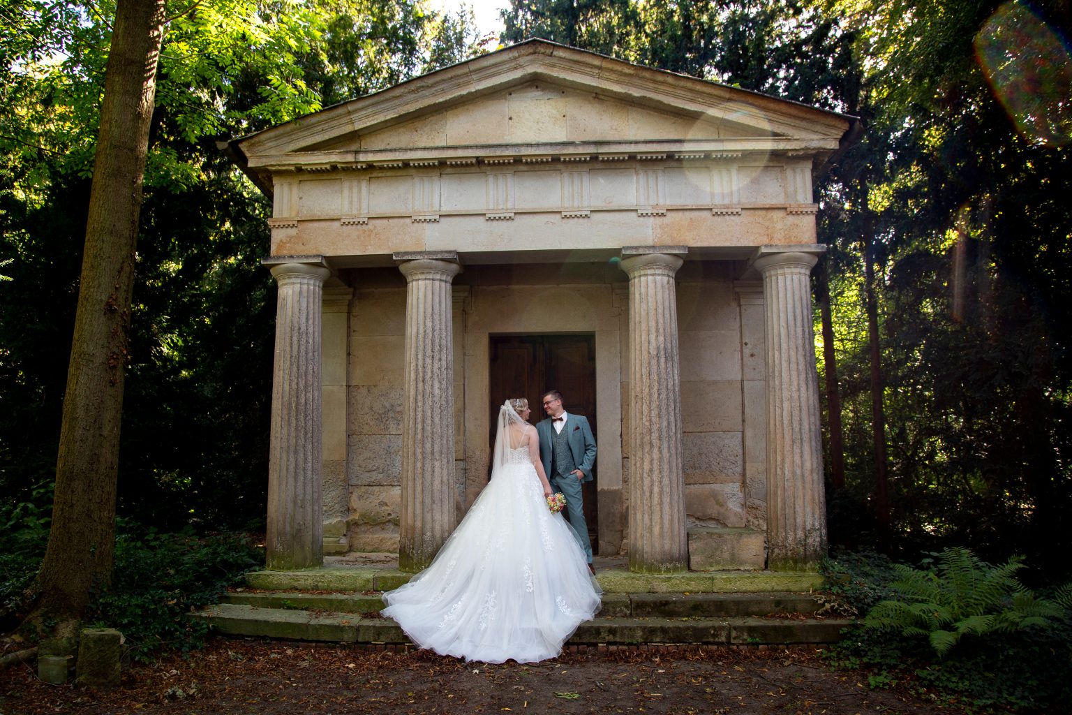 Hochzeitsfoto von Sarah Seiler Fotografie Ein Brautpaar steht vor einem historischen Gebäude und Sarah Seiler Fotografie fotografiert sie.
