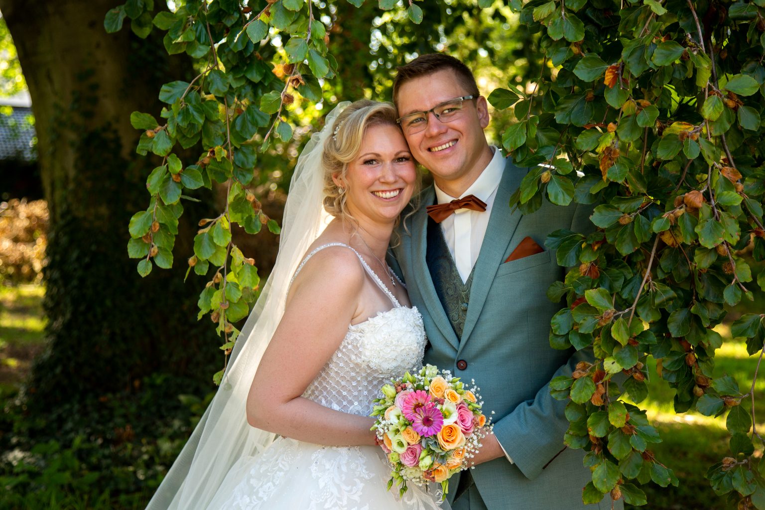 Hochzeitsfoto von Sarah Seiler Fotografie Ein Hochzeitspaar steht vor Weinreben und Sarah Seiler Fotografie fotografiert sie.