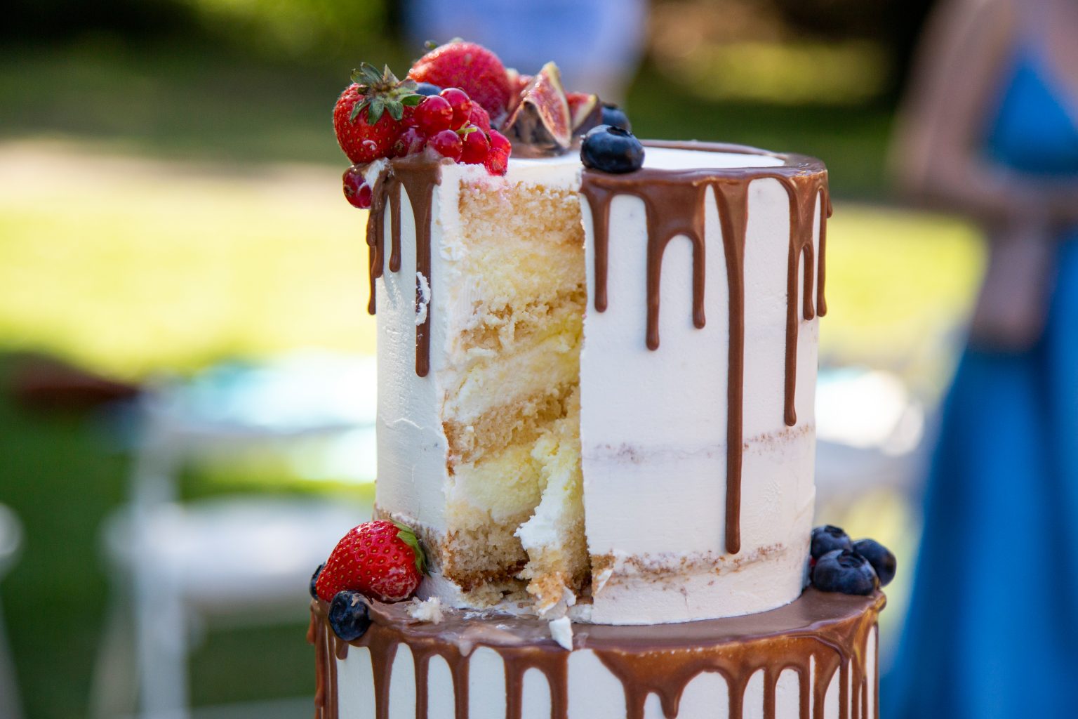 Hochzeitsfoto von Sarah Seiler Fotografie Eine Hochzeitstorte mit Beeren und Dekoelementen wird von Sarah Seiler Fotografie fotografiert.