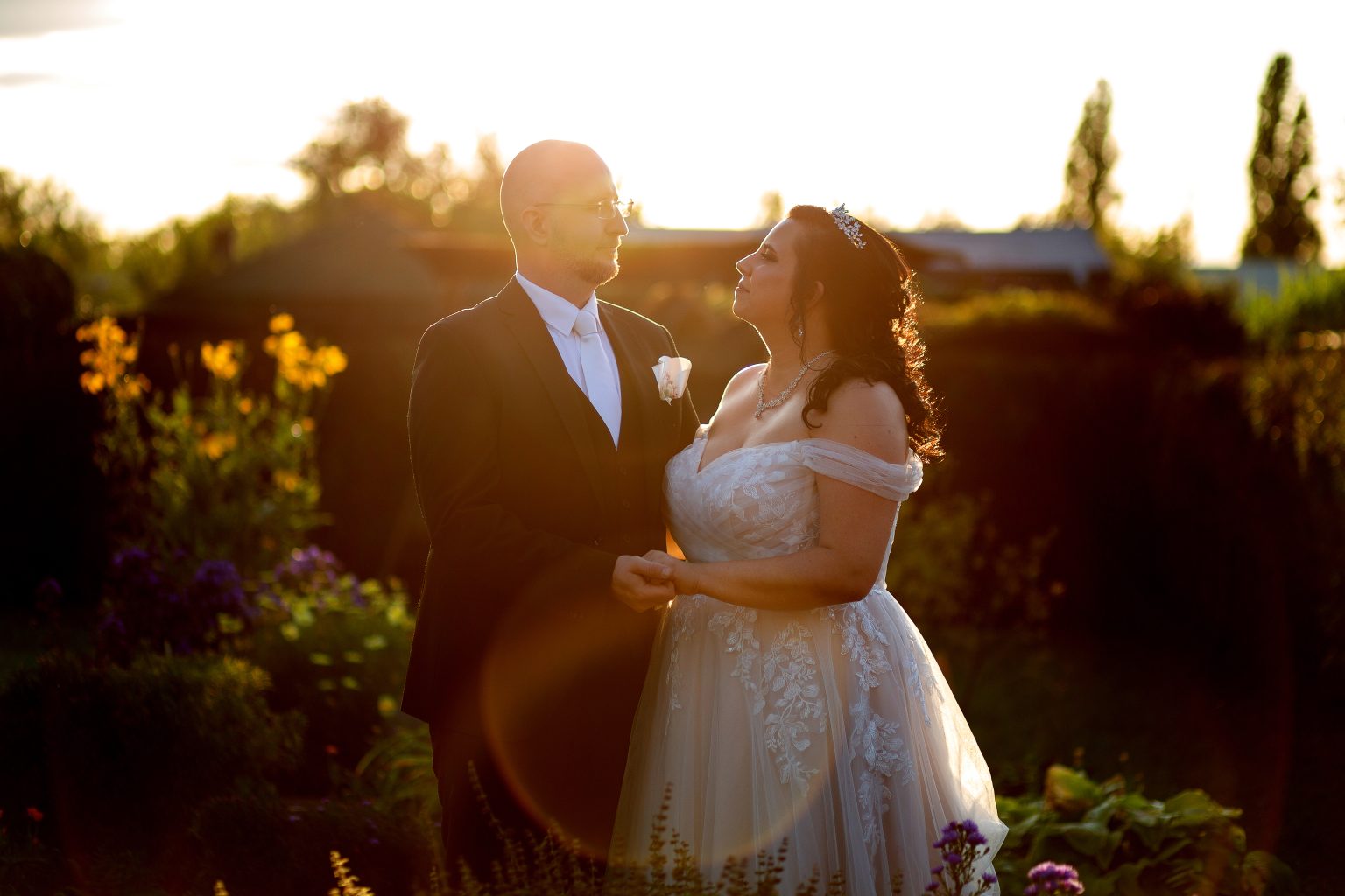 Hochzeitsfoto von Sarah Seiler Fotografie Ein Hochzeitspaar steht im Sonnenlicht und Sarah Seiler Fotografie fotografiert sie.